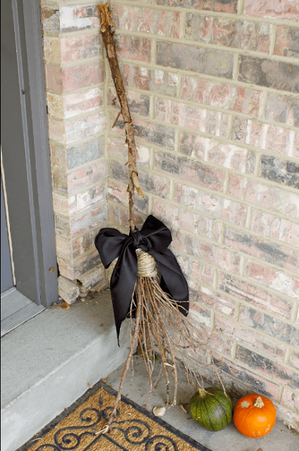 A witches broom leaning against a wall, by a front door